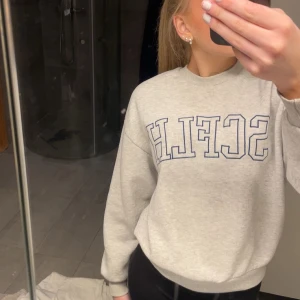 Grå sweatshirt med tryck - Säljer en grå sweatshirt med blått tyck på bröstet. Super skön. Den är lite nopprig vilket man ser på den tredje bilden, men det är inget som ses från långt håll. 