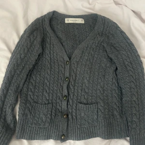 Grå stickad kofta från Zara Knit - Säljer en mysig grå stickad kofta från Zara.  Den har långa ärmar och två fickor där framme. Super fin och mysig ich bra skick. Den är i storlek L men passar mig bra som har S