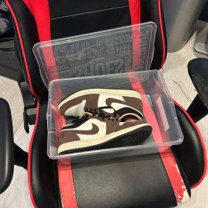 Jordan 1 low mocha  - Säljer ett par Nike Air Jordans i en snygg brun och vit färgkombination. Skorna har en klassisk design med snörning och den ikoniska loggan på insidan. Perfekta för dig som vill ha stil och komfort i ett. Köpt för 3299 i butik 