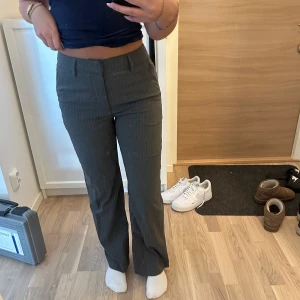 kostymbyxor från Madlady - Snygga grå kostymbyxor från Madlady med diskreta ränder. Byxorna har en klassisk design med hög midja och raka ben, perfekt för en stilren look. De är tillverkade i ett bekvämt material som ger en elegant passform. Jag är 162 som referens❤️ aldrig snvända