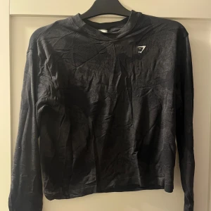 Mjuk träningströja från Gymshark - Superskönt långärmad tröja från Gymshark. Använd fåtal gånger, så gott som ny! Grå/svart mönstrad. Logga fram. Kommer ej till användning tyvärr. 