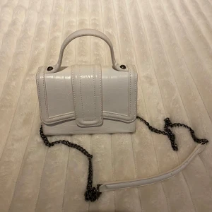 Vit axelväska med kedja - Snygg vit axelväska med kedjedetalj och handtag. 