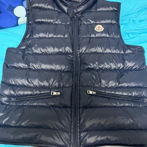Svart dunväst från Moncler - Säljer min mörkblå Moncler Väst i storlek M (passar även S). Den är i toppskick och endast använd i 3 månader. Kvitto medföljer som bevis på äkthet. NFC funkar med.  Anledningen till försäljningen är att jag ska flytta utomlands och inte behöver den längre.  Hör av dig vid intresse!