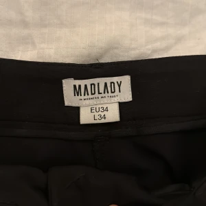 Svarta byxor från Madlady - Snygga svarta byxor från Madlady med hög midja och rak passform. Perfekta för en stilren look. Byxorna har en dragkedja framtill och är tillverkade i ett bekvämt material.