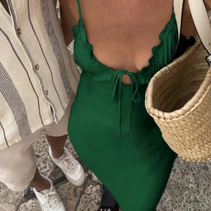 Grön klänning med volangdetaljer - Snygg grön klänning med smala axelband och volangdetaljer vid bysten. Klänningen har en djup v-ringning och knytning framtill. Perfekt för sommarens varma dagar.