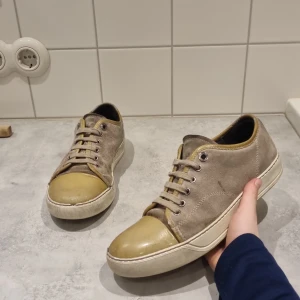 Lanvins - Snygga Lanvins i beige mocka med ett unikt gult tåparti. Skorna har snörning och en vit sula som ger en stilren look. Perfekta för dig som vill ha något annorlunda i garderoben.