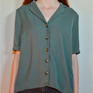 Grön kortärmad skjorta med knappar - Fin, flowy blus från ONLY. Använd ett fåtal gånger, inga defekter. Passar utmärkt till sommaren och är enkel att styla till både jeans, kjol eller uppknäppt som en överdel / extra lager. 