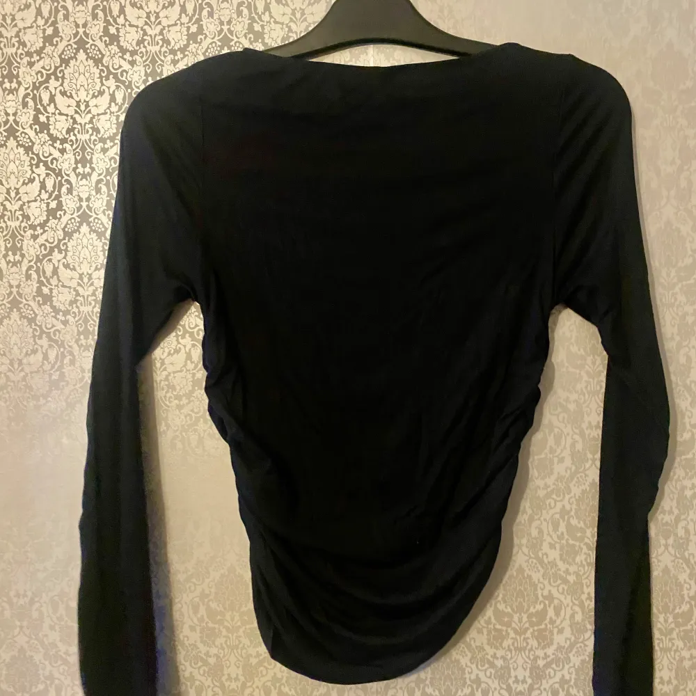 Säljer en stilren svart långärmad topp från H&M Divided. Toppen har en rynkad detalj på sidorna som ger en snygg effekt. Perfekt för att matcha med olika outfits. 🖤. Yläosat.