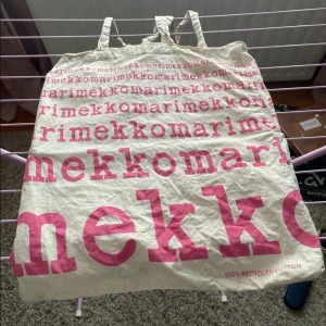 Väska från Marimekko - Säljer en väska från Marimekko med rosa texttryck. Väskan är tillverkad av 100% återvunnen bomull och har två handtag. Perfekt för att bära med sig det nödvändigaste på stan eller till stranden.