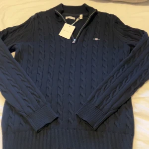 Mörkblå Halfzip Kabelstickad kofta GANT - Säljer en sprillans ny kofta från GANT som aldrig är använd (taggen e kvar).. Det är en halfzip och en kabelstickad modell i samma och är mörkblå Jag säljer den för att jag fick den i julklapp men de köpte för liten. Köpt på kidsbrandstore i julas.