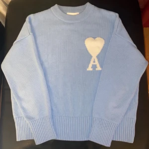 Ljusblå stickad tröja från Ami - Säljer en snygg ljusblå stickad tröja från Ami. Tröjan har långa ärmar och ribbade muddar vid ärmslut och nederkant. Perfekt för en stilren look! 💙