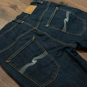 Mörkblå Nudie Jeans - Snygga mörkblå Nudie jeans i fint skick. Det finns en defekt på sista bilden. (Vänster ben). Annars är dom i riktigt fint skick✅. Tveka inte på att ställa frågor🤝🏼. Nypris ligger runt 1500kr!