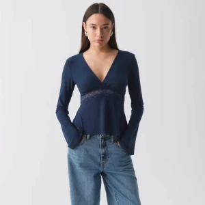 Mörkblå v-ringad topp med spetsdetalj GINATRICOT - Mörkblå topp med v-ringning och spetsdetalj under bysten. Långa utsvängda ärmar och en figurnära passform. HELT NY utan prislapp! Säljer då de inte är min stil. Sitter så bra och är från Gina Tricot. Storlek 38 men passar även 36.