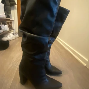 Svarta stövlar med spetsiga tå - Snygga svarta stövlar i skinn med spetsig tå och klack. Perfekta för en stilren look. De har en elegant design som passar till många olika outfits.
