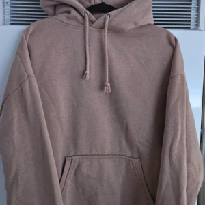 Beige hoodie med ficka - Säljer en stilren beige hoodie med en stor ficka framtill och justerbar huva. Perfekt för en avslappnad look. Passar bra till både jeans och mjukisbyxor.