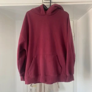 Vinröd hoodie - Säljer en vinröd hoodie med en stor ficka framtill och en bekväm huva. Perfekt för kyliga dagar och avslappnade stunder. Passar bra till jeans eller mjukisbyxor.