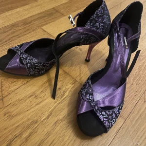 Lila och svarta klackskor med blommönster - Eleganta lila klackskor med svart blommönster och korsade remmar