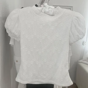 Svart offshoulder topp med volang - Set med en vit blomig topp med puffarm och en svart minikjol som ser väldigt söt ut. Ger en coquette, cute-girl vibe. Köp en hel set här för 80kr. Annars 50kr för varje plagg. 