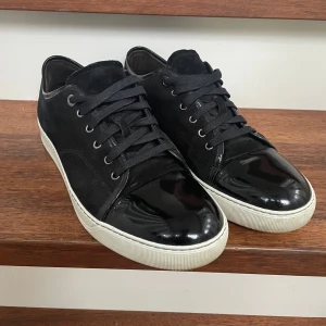 Svarta Lanvin Uk 10 - Snygga svarta sneakers från Lanvin. Säljes pågrund av att de inte längre används. Väldigt bra skick och inga skador varken innuti eller på utsidan. Skick (7,5/10). Uk 10 och sitter som 44-46 i europeisk storlek. Priset går att diskutera och skriv gärna om du undrar över bilder eller några frågor!