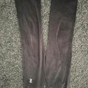 Svarta velourbyxor från Juicy Couture - Snygga svarta velourbyxor från Juicy Couture med det ikoniska 'Juicy' trycket på baksidan. 