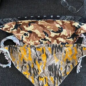 Fyra bandanas i olika mönster - Säljer fyra bandanas: en svart med klassiskt paisleymönster, en beige-brun camo, en grå-gul camo och en pastellrutig med små bollar längs kanten. Perfekta att knyta i håret eller runt huvudet för en cool look.50kr styck eller allt för 150kr
