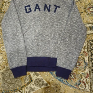 Gråmelerad sweatshirt från GANT - Säljer en gråmelerad sweatshirt från GANT i storlek S. Tröjan har mörkblå ribbade muddar vid ärmslut och nederkant och GANT logga i mörkblått framtill. Perfekt för sen chill look.