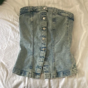 Jeans tubtopp från H&M Divided - Säljer en snygg jeans tubtopp från H&M Divided i ljusblå denim. Toppen har knappar framtill🤍