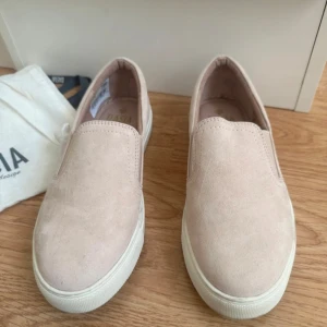 Ljusrosa loafers från Dasia - Snygga slip-on sneakers från Dasia i ljusrosa med vit platt sula. Skorna har elastiska partier på sidorna för enkel påtagning och en stilren, minimalistisk look. Perfekta för dig som gillar en clean och avslappnad stil