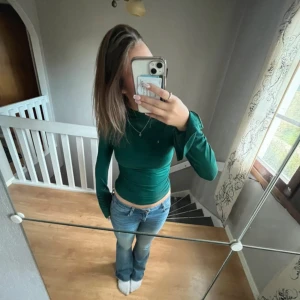 Grön tight långärmad polotröja - Snygg grön polotröja med tight passform och långa ärmar. Tröjan är enkel men stilren, perfekt att matcha med jeans eller kjol. Materialet känns mjukt och stretchigt, vilket gör den bekväm att bära hela dagen.