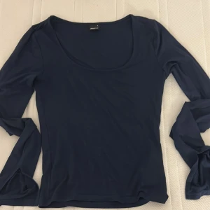 Mörkblå långärmad topp Gina Tricot - En stilren mörkblå långärmad topp från Gina Tricot med rundad, djup urringning. Tunn och mjuk i materialet, perfekt för lager-på-lager eller som den är. Använd fåtal gånger, inga synliga slitage.