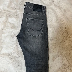 Grå slim jeans från Jack & Jones - Jack & Jones jeans i modellen Slim Glenn, i gråtvättad färg. Storlek W29 L32. I princip nyskick – använda max ett par gånger. Snygg slim passform. Materialet är mjukt och stretchigt jeans, perfekt för en trendig vardagslook.