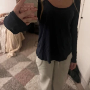 Marinblå långärmad topp från H&M - En svart långärmad topp från H&M i ekologisk bomull. Modellen är tight och har en rund, något djupare ringning. Perfekt att styla med jeans eller mjukisbyxor för en chill look.