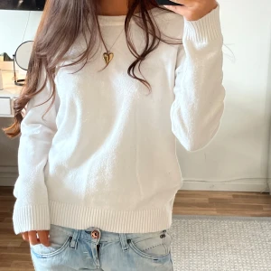 Vit stickad tröja från Vila - Klassisk vit stickad tröja från Vila med rund halsringning och ribbade muddar vid ärmslut och nederkant. Tröjan har en enkel och clean look, perfekt att matcha med jeans eller kjol. Långärmad och i mjukt material som känns skönt mot huden. Sitter mer som S