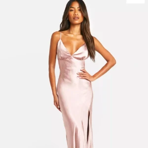 Rosa långklänning med slits - Säljer en satin klänning  med smala axelband, djup v-ringning och hög slits framtill. Klänningen har en figurnära passform 