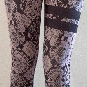 Leggings med ormmönster och svarta ränder - Snygga leggings med ormmönster i svart och ljusrosa, samt två breda svarta ränder på ena låret. 