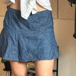 Blå jeanskjol från Gap 1969 - Säljer en blå jeanskjol från Gap 1969 med snygg utsvängd form och paneldetaljer. Kjolen är kort och har klassisk denimlook, perfekt att styla med sneakers eller boots. Midjan är normal och materialet är mjukt jeans. Superenkel att matcha till olika outfits!