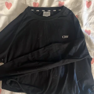Svart långärmad tröja från ICANIWILL - Svart långärmad tröja från ICANIWILL med diskret logga på bröstet. Enkel och stilren design med rund halsringning. Perfekt för dig som gillar en clean look och vill ha något bekvämt till träning eller chill.