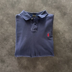 Långärmad piké från Ralph Lauren - Långärmad pikétröja i klassisk marinblå. Otroligt skön  och stilig, matchar med allt. Fantastiskt skick, storlek M. Tyvärr fast pris men byten är intressanta!