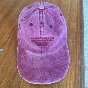 Rosa keps från House Brand - Snygg rosa keps från House Brand med broderad logga framtill. Kepsen har en klassisk böjd skärm och synliga sömmar som ger en cool vintagekänsla. 