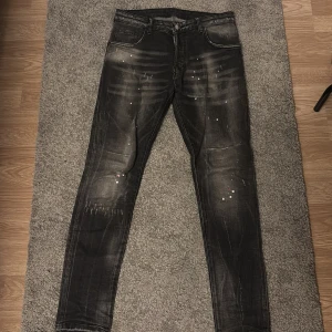 Svarta skinny jeans från Dsquared2 - Snygga svarta skinny jeans från Dsquared2 med coolt sliten look och färgstänk-detaljer. Jeansen har klassisk femficksdesign, DSQ2 DENIM-patch bak och är tillverkade i stretchig bomullsdenim för en bekväm passform. Använda bara ett fåtal gånger. Vill bli av me de snabbt!
