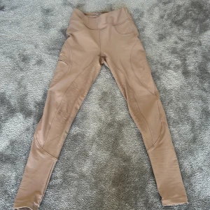 Beige ridleggings från Lope XS - Snygga beige ridleggings från Lope med hög midja och coola detaljer. Byxorna har praktiska bakfickor med guldknappar och mönstrat silikon-grip på insidan av benen för extra grepp. Super sköna men säljs då storleken inte passar. 🌸