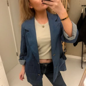 Oversized jeanskavaj i blå denim - Säljer en oversized kavaj i blå denim med stora fickor framtill och knappar. Jackan har klassisk krage och uppvikta ärmar för en chill vibe. Perfekt att slänga över en t-shirt för en avslappnad look. Använd en gång, som ny!❤️