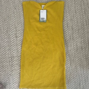 Gul Miniklänning - Snygg gul ribbad tubklänning från H&M. Klänningen är kort och har en figurnära passform. Storlek Xs. Prislappen kvar på. Säljer för 100 kr!