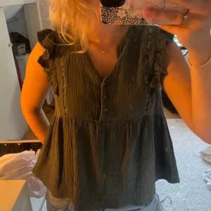 Mörkgrön blus med volang från Sweewë - Supersöt mörkgrön blus från Sweewë, köpt från butiken missäy!  volangdetaljer på axlarna och knappar framtill. Perfekt för dig som gillar romantiska och avslappnade vibes.