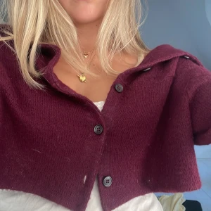 Vinröd croppad kofta från Marni - Superfin vinröd croppad kofta från Marni med tre knappar framtill och bred krage. Koftan är stickad och har trekvartsärmar, perfekt att slänga över ett linne eller t-shirt för en chill men snygg look.