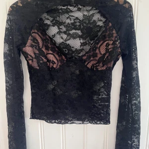 Svart spetsblus med lång ärm - Fin spetts tröja med djup urringning. Aldrig använd pågrund av för liten. Liten i storleken så skulle mer passa som xs