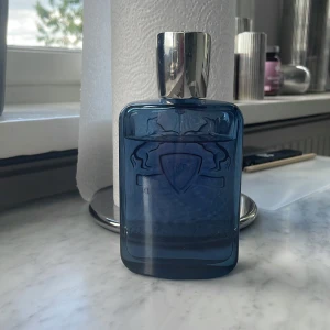 Sedley-Parfyms de marley - Snygg parfym från Parfums de Marly i en stilren blå glasflaska med silverfärgat lock. Flaskan är nästan full-runt 100 ml av 125ml- Doften har citrus, aromatiska och träiga toner med inslag av amber, lavendel och musk 
