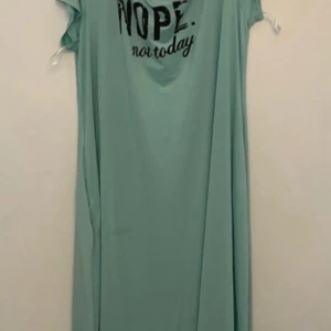 Plus-size Mintgrön långklänning med tryck - Lång plus-size, loose-fit klänning i mintgrönt med svart texttryck 'NOPE. not today' framtill. Klänningen har korta ärmar och är tillverkad i ett mjukt, stretchigt material som känns skönt mot huden. Perfekt för chill dagar när du vill vara bekväm men ändå ha stil. Samt har fickor på båda sidorna! Helt ny!
