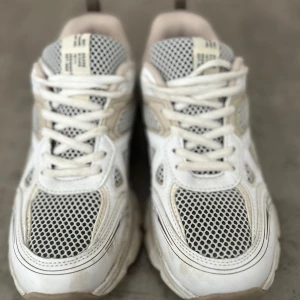 Vita chunky sneakers med meshdetaljer - Snygga vita sneakers med chunky sula och svart mesh på ovandelen. Skorna har vita snören och beige detaljer längs sidorna. Perfekta för dig som gillar sportig och trendig stil. Ovandelen är i syntet och mesh för extra andningsförmåga.