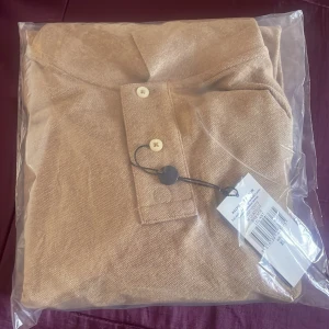 Beige stickad pikétröja Polo Ralph Lauren XL - Snygg beige stickad långärmad pikétröja från Ralph Lauren i storlek XL. Tröjan har klassisk krage, två knappar framtill och är tillverkad i ett mjukt stickat material. Perfekt för dig som gillar en clean och stilren look med premiumkänsla. Oöppnad och ingen användning alls. 